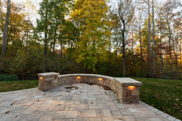 Picturesque backyard view in autumn season with patio pavers and stone wall, automn leaves, and colorful woods in the background.
